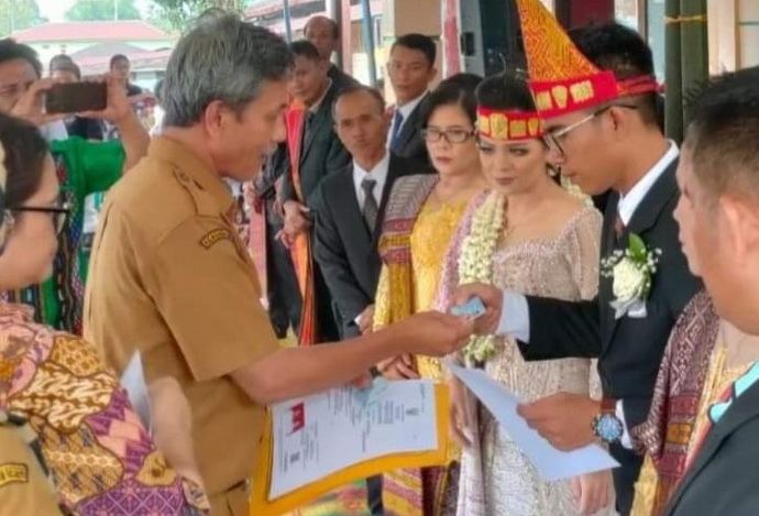 Kepala Disdukcapil Pakpak Bharat Petrus Saragih SE MM menyerahkan dokumen kependudukan bagi dua pasangan yang melangsungkan pernikahan, Rabu (11/10/2023).